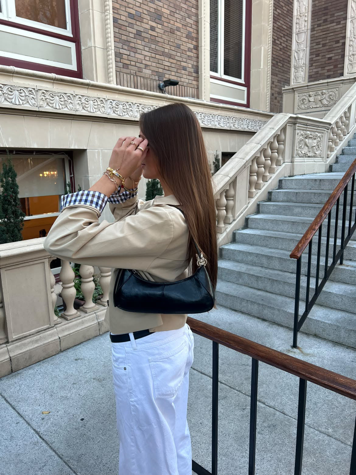 Beige Yours Truly cropped trench with gingham cuffs, styled with white trousers on stone steps.